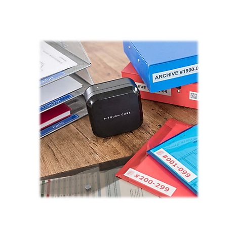 Ein schwarzes P-Touch Cube BeschriftungsgerÃ¤t neben beschrifteten Ordnern und Mappen auf einem Holztisch.