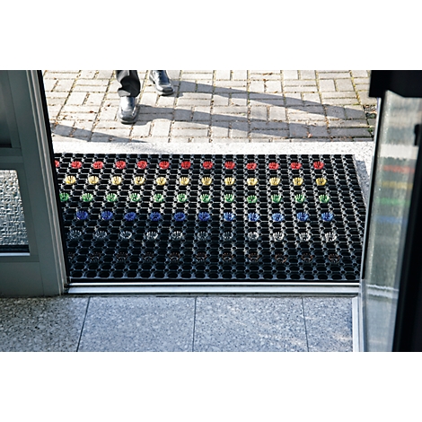 Black doormat with colorful hands. Person in shoes entering room through door.