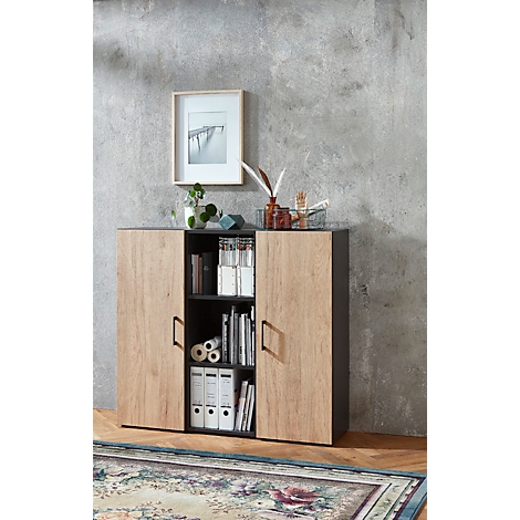 Un meuble en bois avec un cadre noir. Des livres et des dossiers se trouvent sur les étagères ouvertes. Au-dessus, une image et des décorations.