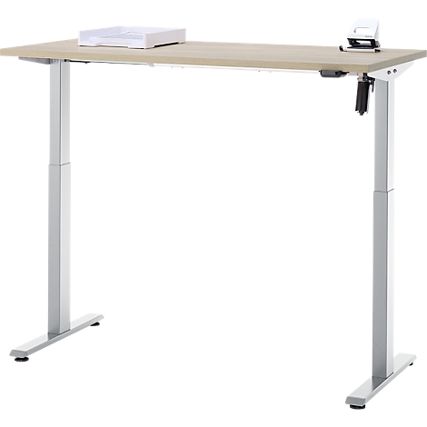 Een in hoogte verstelbaar bureau met licht hout en zilveren poten. Bovenop staat een papierbak en een perforator.