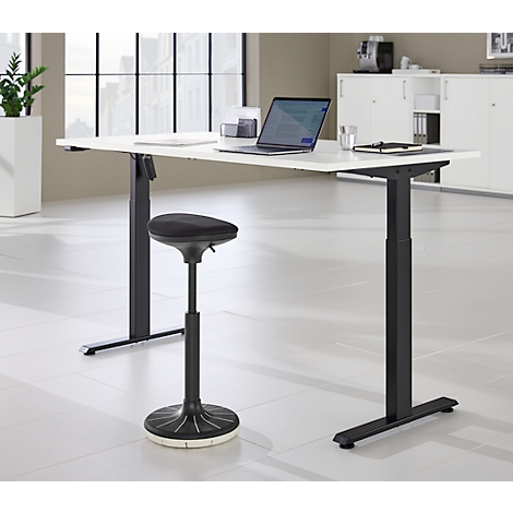 In hoogte verstelbaar bureau met kruk. Een laptop staat op het bureau.