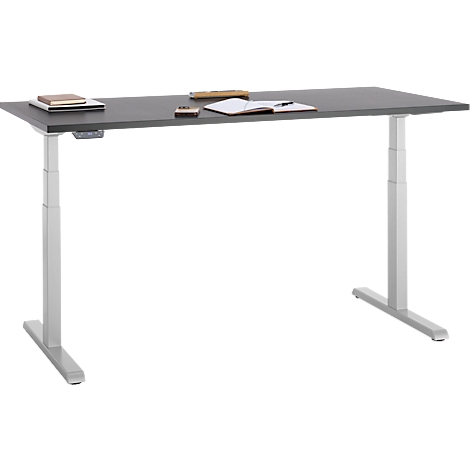 Een in hoogte verstelbaar grijs bureau met benodigdheden: notitieboek, pen, boek en telefoon.