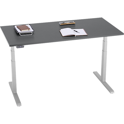 Grijze in hoogte verstelbare bureau met notitieblokken en pennen. Het bureau heeft zilveren poten.