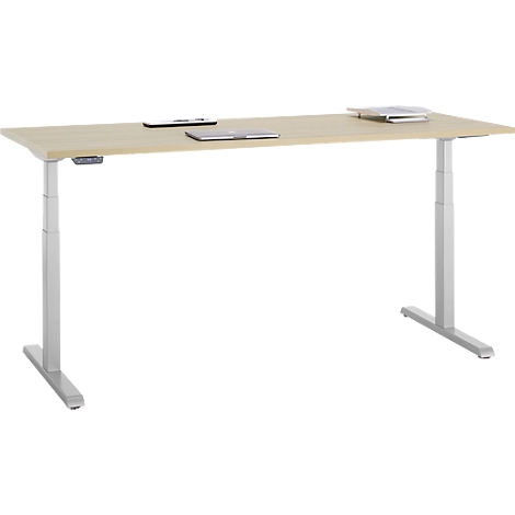Een lichtgekleurde, in hoogte verstelbare bureau met een laptop, tablet en smartphone op het tafelblad. De poten zijn zilver.