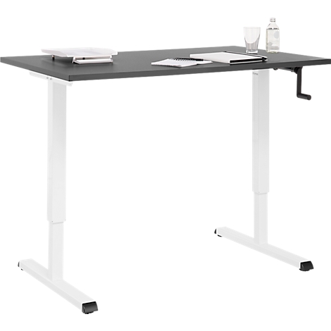 Un bureau réglable en hauteur avec un plateau sombre et des pieds blancs, verre et bouteille en arrière-plan.