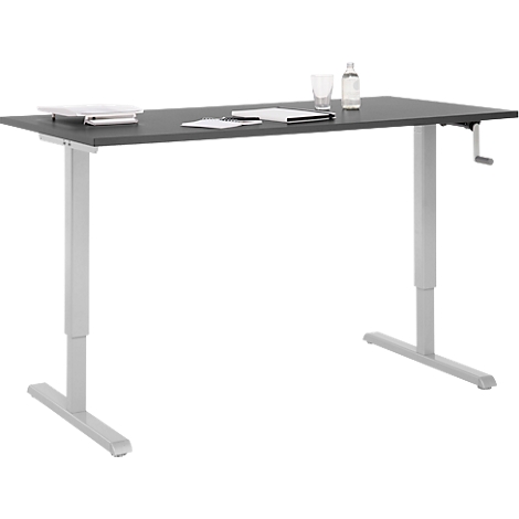 Un bureau gris réglable en hauteur avec un plateau gris, un cadre blanc et une manivelle. Il y a du papier et une bouteille dessus.