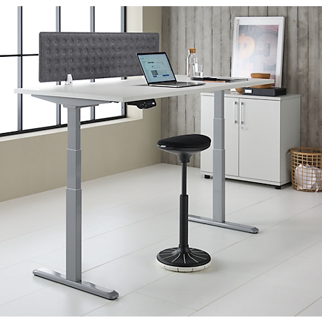 Een in hoogte verstelbaar bureau met laptop, stoel, grijze gewatteerde muur en accessoires. Heldere, moderne kantooropstelling.