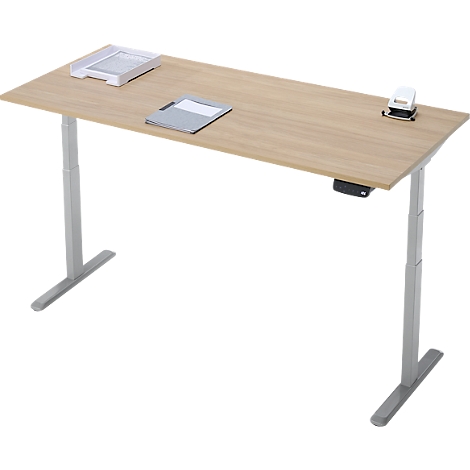 Un bureau beige réglable en hauteur avec des pieds argentés et quelques accessoires de bureau.
