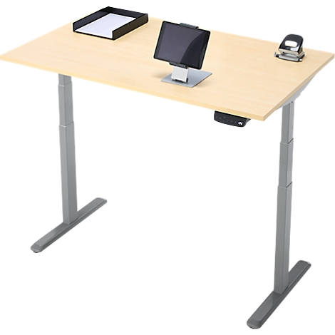 Un bureau réglable en hauteur en bois clair. Sur le plateau se trouvent une tablette, un porte-papier et une perforatrice.