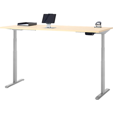 Bureau brun clair réglable en hauteur avec pieds argentés. Sur le dessus de la table se trouvent une tablette, une perforatrice et un bac.