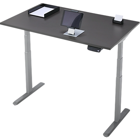 Un bureau gris réglable en hauteur avec un plateau de table sombre. Dessus : tablette, porte-papier et papier.