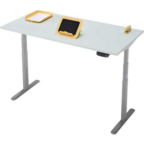Un bureau réglable en hauteur, gris clair, avec des plateaux jaunes et un support pour tablette. Il y a une agrafeuse sur le bureau.