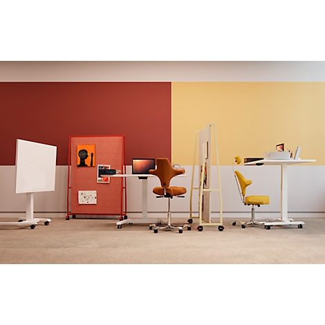 Configuration de bureau avec tables réglables en hauteur, chaises et séparateurs de pièce. Mur rouge et jaune, sol gris.