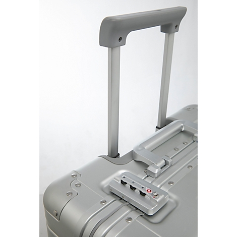 Gros plan sur une valise argentée avec poignée extensible, cadenas à combinaison et certification TSA.