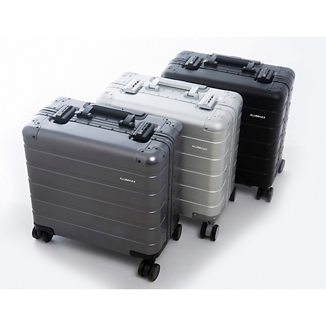 Trois valises en aluminium dans des tons gris, argent et noir. Équipées de roues et de poignées, elles sont côte à côte sur fond blanc.