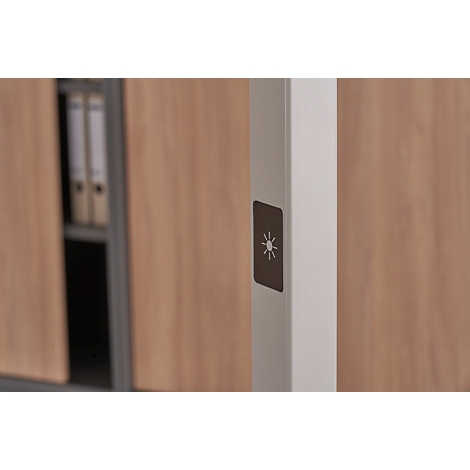 Close-up: Bright column with dark brown switch, sun symbol. Wooden cabinet, folders in the background.