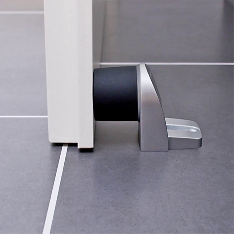 Gros plan d'une butée de porte. La butée est argentée et maintient une porte blanche.