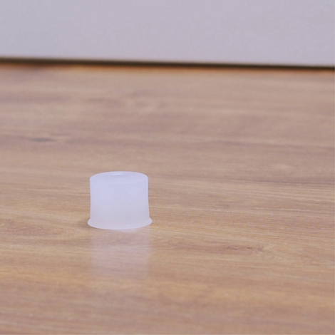 Un objet blanc de forme cylindrique est posé sur une surface en bois. L'arrière-plan est flou.