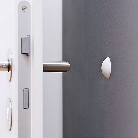 Gros plan d'une porte avec une poignée en métal, un cadre de porte blanc et un élément blanc semi-circulaire sur le mur.