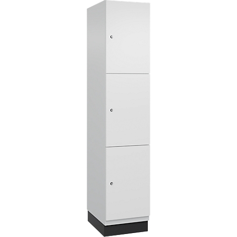 Witte hoge kast met drie deuren. Elke deur heeft een kleine ronde handgreep. De kast staat op een zwarte voet.