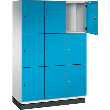 Blauwe locker met open vak. Negen compartimenten, deuren met kleine knoppen. Witte behuizing, zwarte voet.
