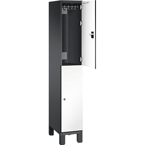 Ein Spind, die obere Tür ist geöffnet. Innen sind Kleiderhaken und Lüftungslöcher zu sehen. Die untere Tür ist halb geöffnet.