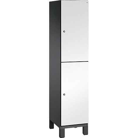 Schrank in Weiß mit grauen Seitenteilen und vier Beinen. Zwei Türen, jeweils mit einem kleinen silberfarbenen Knauf.