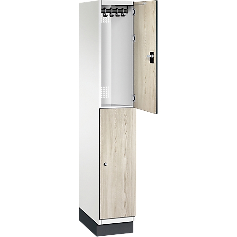 Ein weißer Schrank mit offener Tür, innen Kleiderhaken. Die Tür hat Holzmaserung.