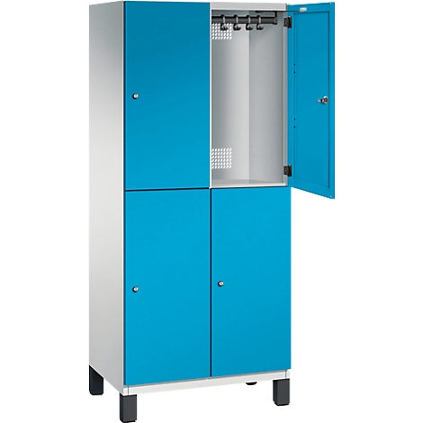 Ein blauer Spind mit vier Türen, eine Tür geöffnet. Aufhängungen im offenen Fach.