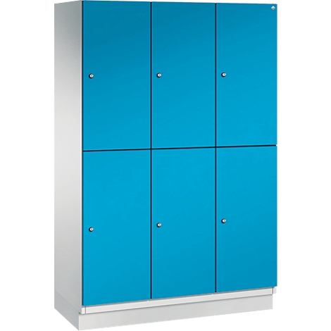 Schrank mit sechs blauen Türen und silberfarbenen Knöpfen. Der Schrank steht auf einem weißen Sockel.