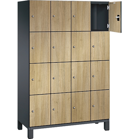 Ein Schrank mit 15 Fächern aus Holz, eins davon geöffnet. Hellbraune Türen mit kleinen Griffen und anthrazitfarbenem Rahmen.