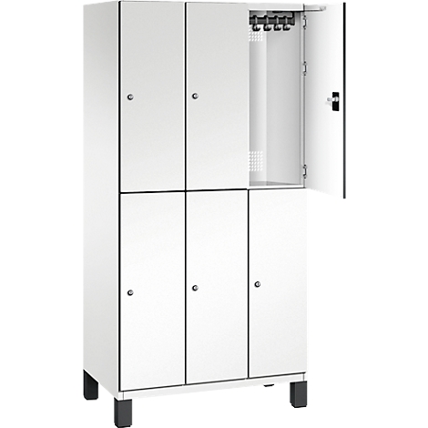 Weißer Spind mit geöffneter Tür. Hakenleiste, schwarze Füße, schwarze Konturen.