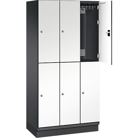 Ein Spind in Weiß und Dunkelgrau, ein Fach ist geöffnet. Im Inneren Haken und Belüftungsschlitze.