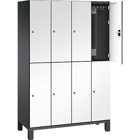 Ein weiß-grauer Spind mit acht Türen, eine davon geöffnet. Im Inneren sind Haken zu sehen.