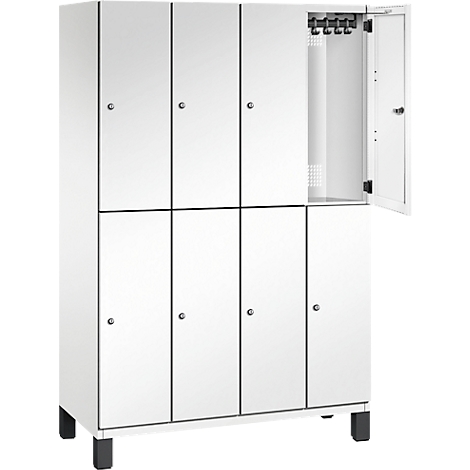 Weißer Spind mit acht Türen, eine Tür geöffnet. Schwarze Rahmen und Griffe. Haken für Kleidung im Inneren.