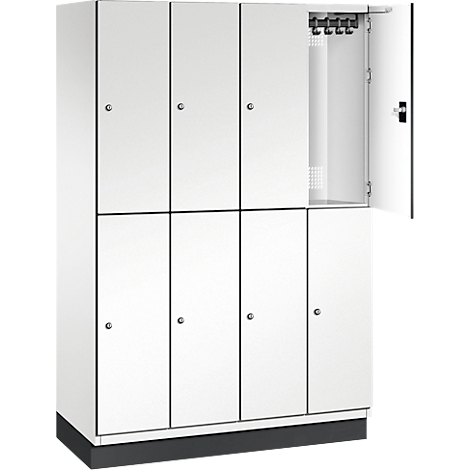 Weißer Spind mit offener Tür, in der Haken zu sehen sind.