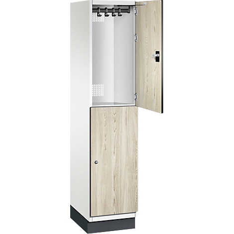 Een witte locker met gedeeltelijk open deuren, de deur van hout, kapstokken aan de bovenkant.