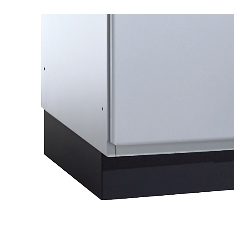 Ecke eines weißen Schranks mit einer schwarzen Sockelleiste und einem grauen Streifen dazwischen.