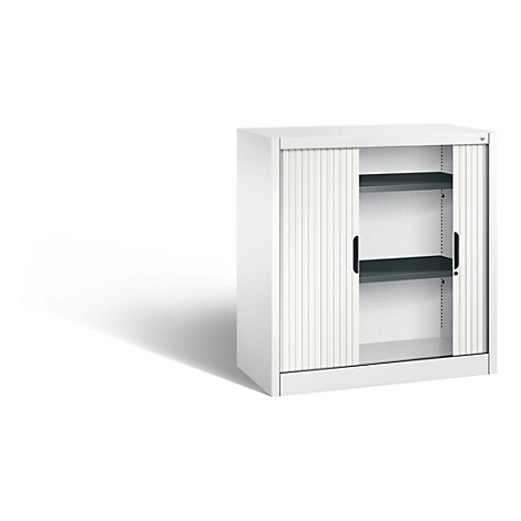 White cabinet with roller shutters. Black handles and two shelves. Shadow on the left.
