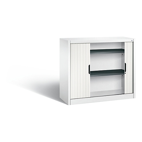 White cabinet with two shelves and roller shutter. Black handles and gray shelves, shadow.
