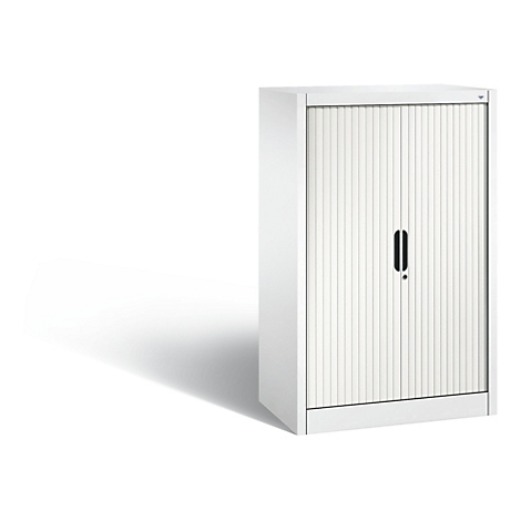 Weißer Rollladenschrank, der Schatten wirft. Das Möbelstück hat eine geriffelte Front und einen schwarzen Griff.