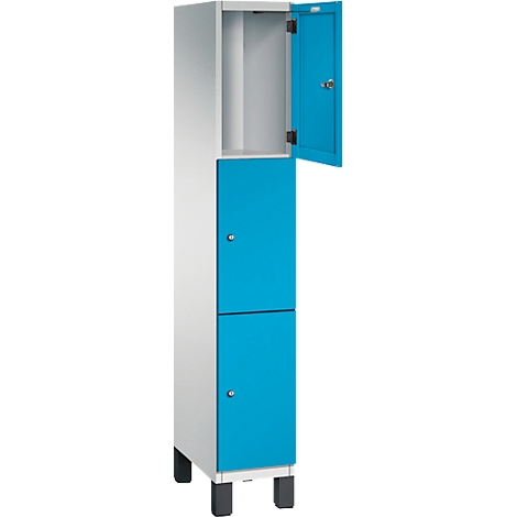 Schrank in Hellgrau mit türkisfarbenen Türen, eine Tür geöffnet. Unten zwei Fächer mit runden Griffen, oben ein Fach offen.