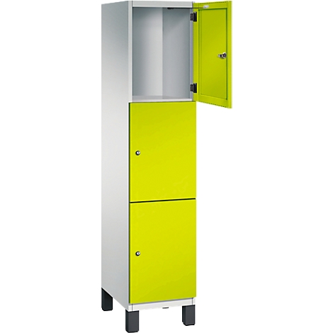 Weißer Schrank mit zwei gelb-grünen Türen, eine davon geöffnet. Schwarze Füße.