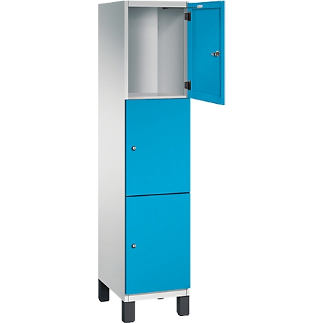 Schrank in Weiß mit zwei blauen Türen, eine davon offen. Schwarze Füße.