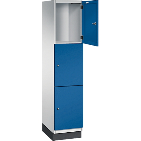 Zweiteiliger, weiß-blauer Spind, obere Tür offen.