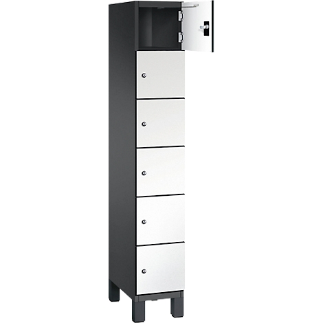 Hoher, grauer Schrank mit weißen Türen. Eine Tür ist geöffnet. Er steht auf kleinen, schwarzen Füßen.