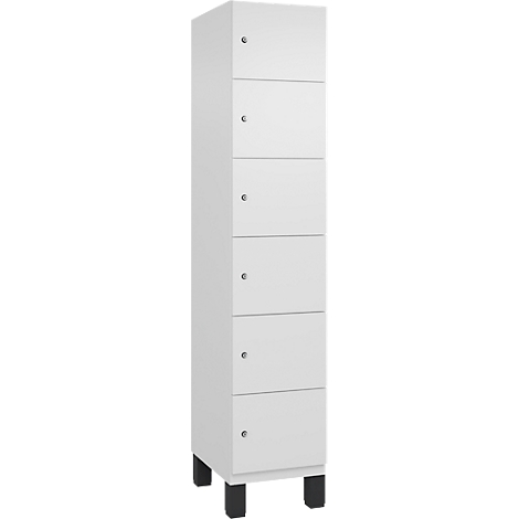 Ein hoher, weißer Schrank mit sechs Schubladen. Schwarze Füße. Kleine, silberne Griffe.