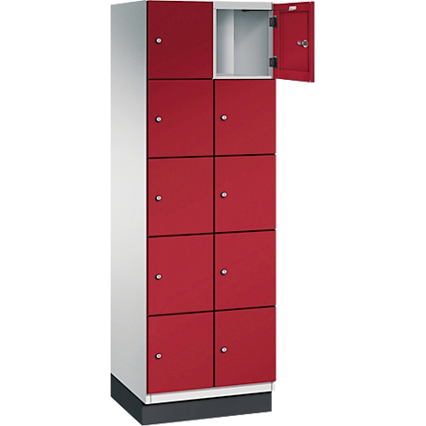 Ein roter Spind, eine Tür geöffnet. Oben weiß, rot, unten. Grauer Sockel.