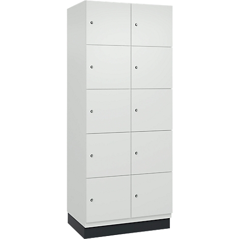 Weißer Schrank mit zehn Türen und kleinen Knöpfen. Der Schrank steht auf einem dunklen Sockel.