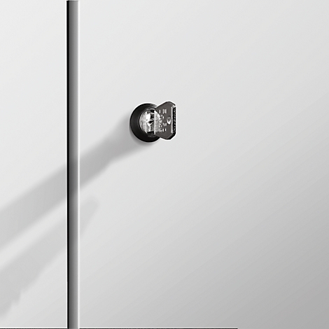 Ein Detailfoto eines schwarzen Türschlosses mit Schlüssel auf einer weissen Tür. Der Schatten des Schlüssels fällt nach unten.